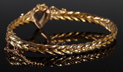 Lot 58 - A yellow metal and split pearl hinged bangle...