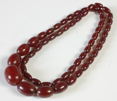 Lot 243 - A graduated red amber type bead necklace, 52.4...