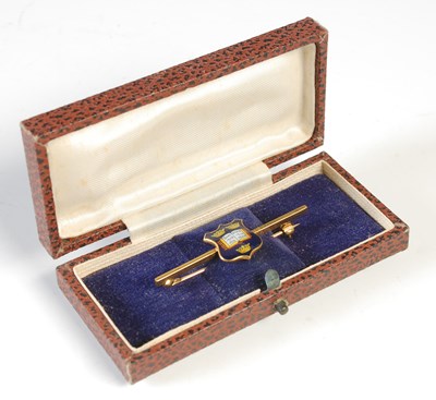Lot 57 - A yellow metal and enamel bar brooch centred...