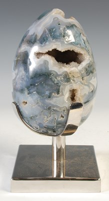 Lot 328 - A carved moss agate crystal geode egg, raised...