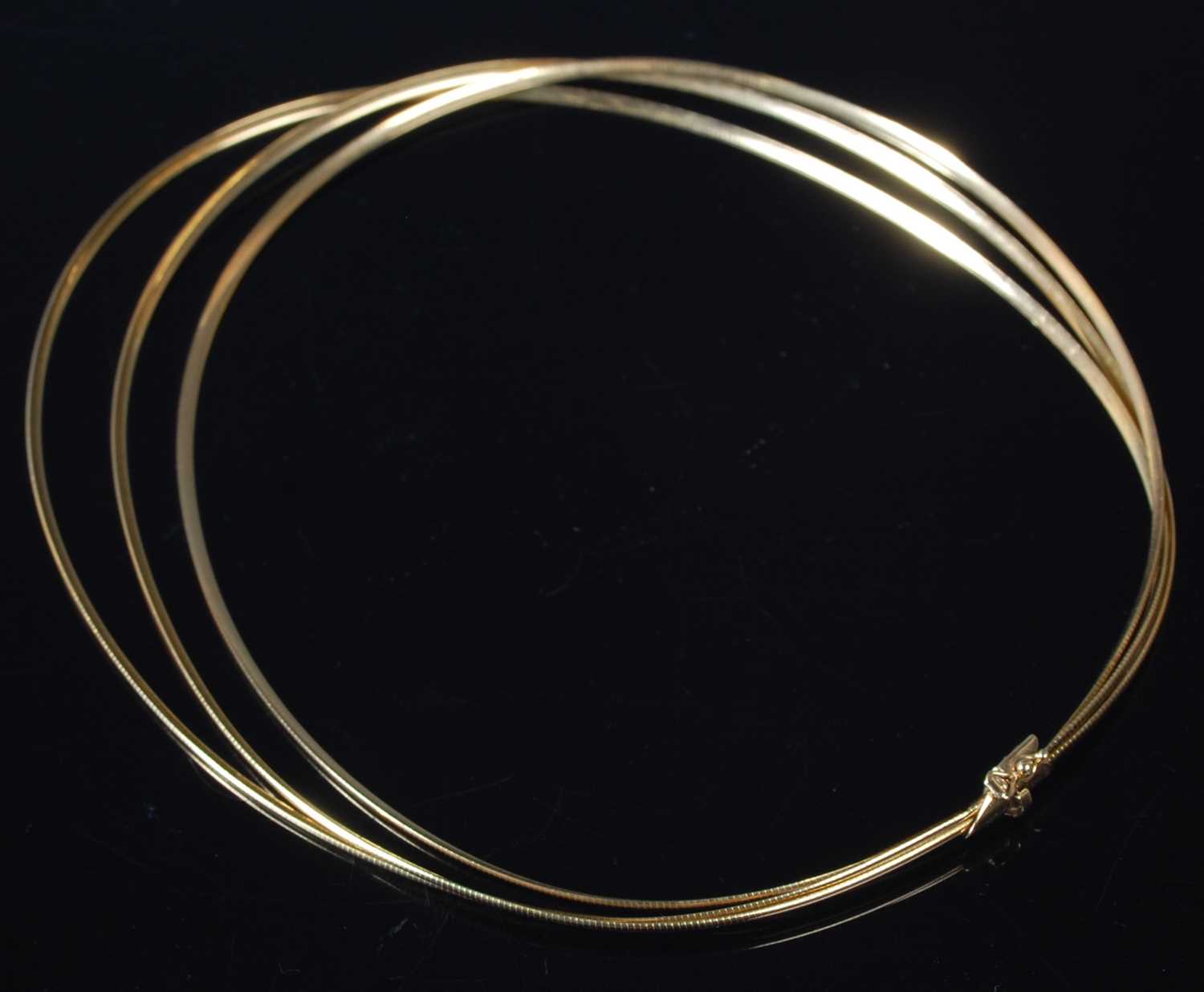 Lot 11 - A triple strand 18ct gold necklace, stamped...