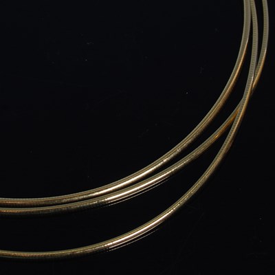 Lot 11 - A triple strand 18ct gold necklace, stamped...